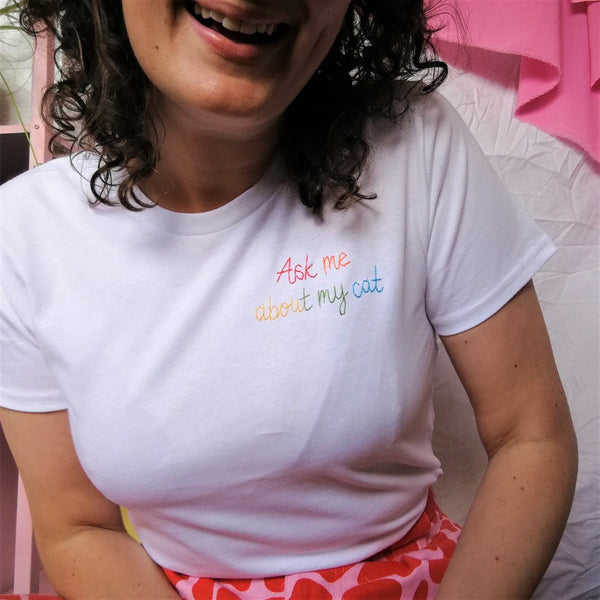 organic cotton white slogan tshirt, embroidered with ask me about my cat in rainbow threads. funny birthday gift for cat mum or cat lover