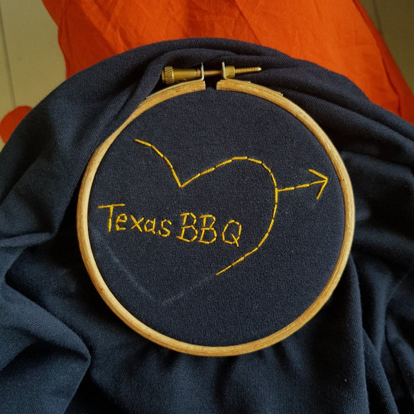 hand embroidered t-shirt, made from navy organic cotton, and hand embroidered with a personalised love heart 'texas bbq'