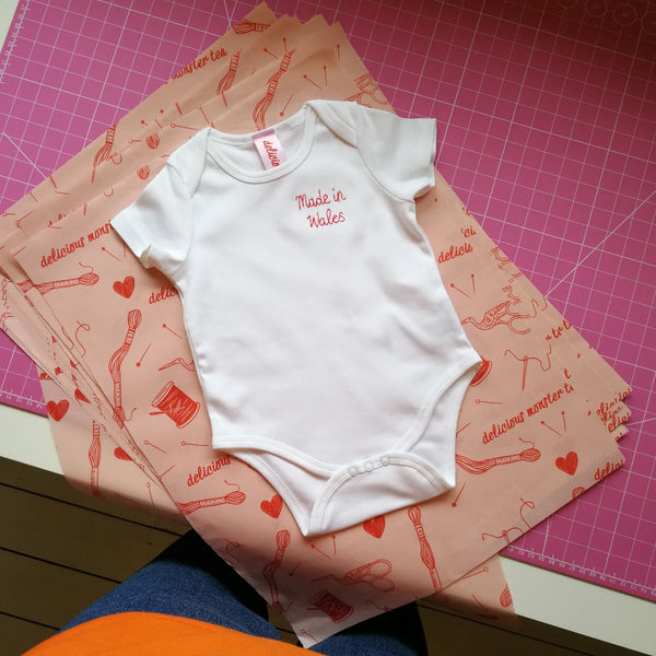 personalised baby grow, made from white organic cotton, and hand embroidered with 'made in wales', as a gift for welsh new born baby