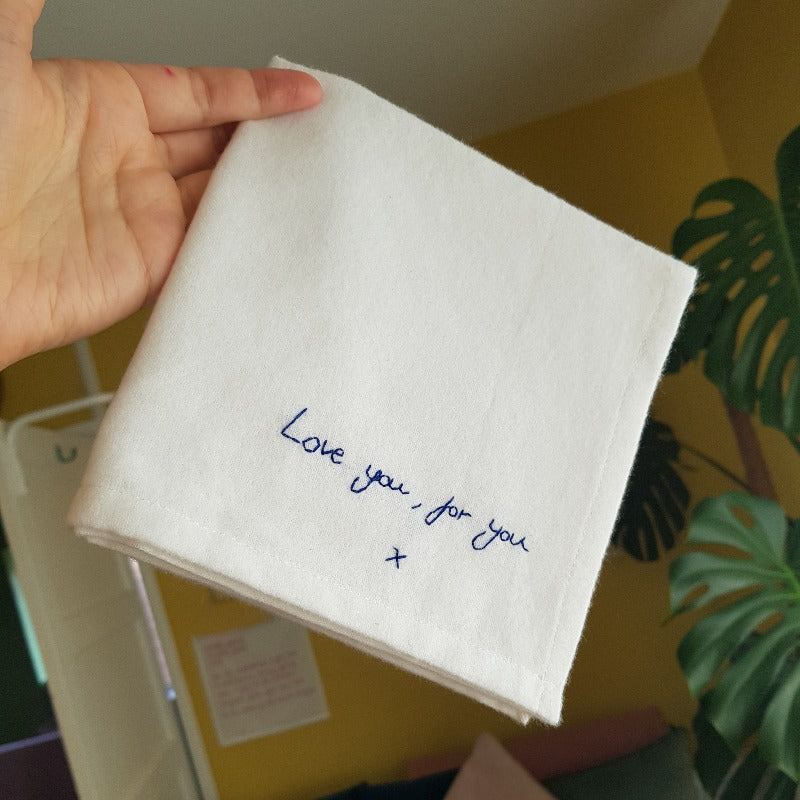 A white cotton handkerchief with navy embroidered handwriting that reads 'Love you, for you x'