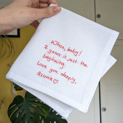A white cotton handkerchief with red embroidered handwriting that reads 'Whoa, baby! 7 years is just the beginning. Love you deeply, Azonia x'