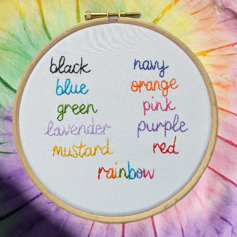 a list of colours, hand embroidered onto white fabric