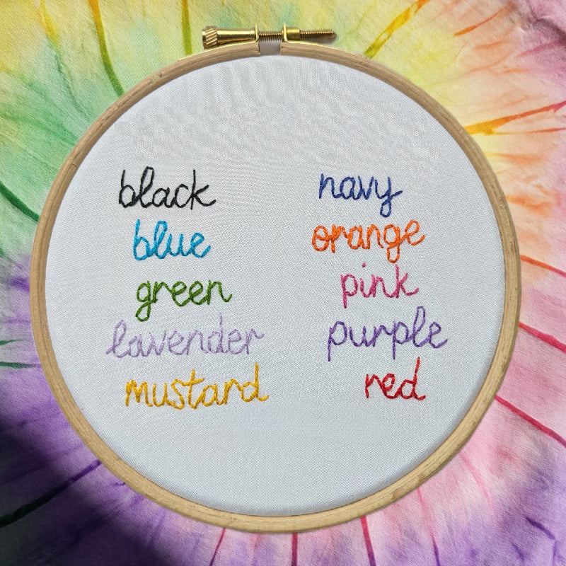 a list of colours, hand embroidered on white fabric