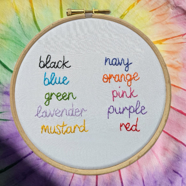 a list of colours, hand embroidered on white fabric