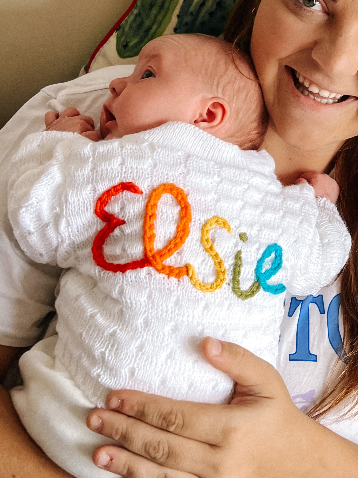 Baby wearing personalised rainbow baby cardigan with colourful hand embroidered name