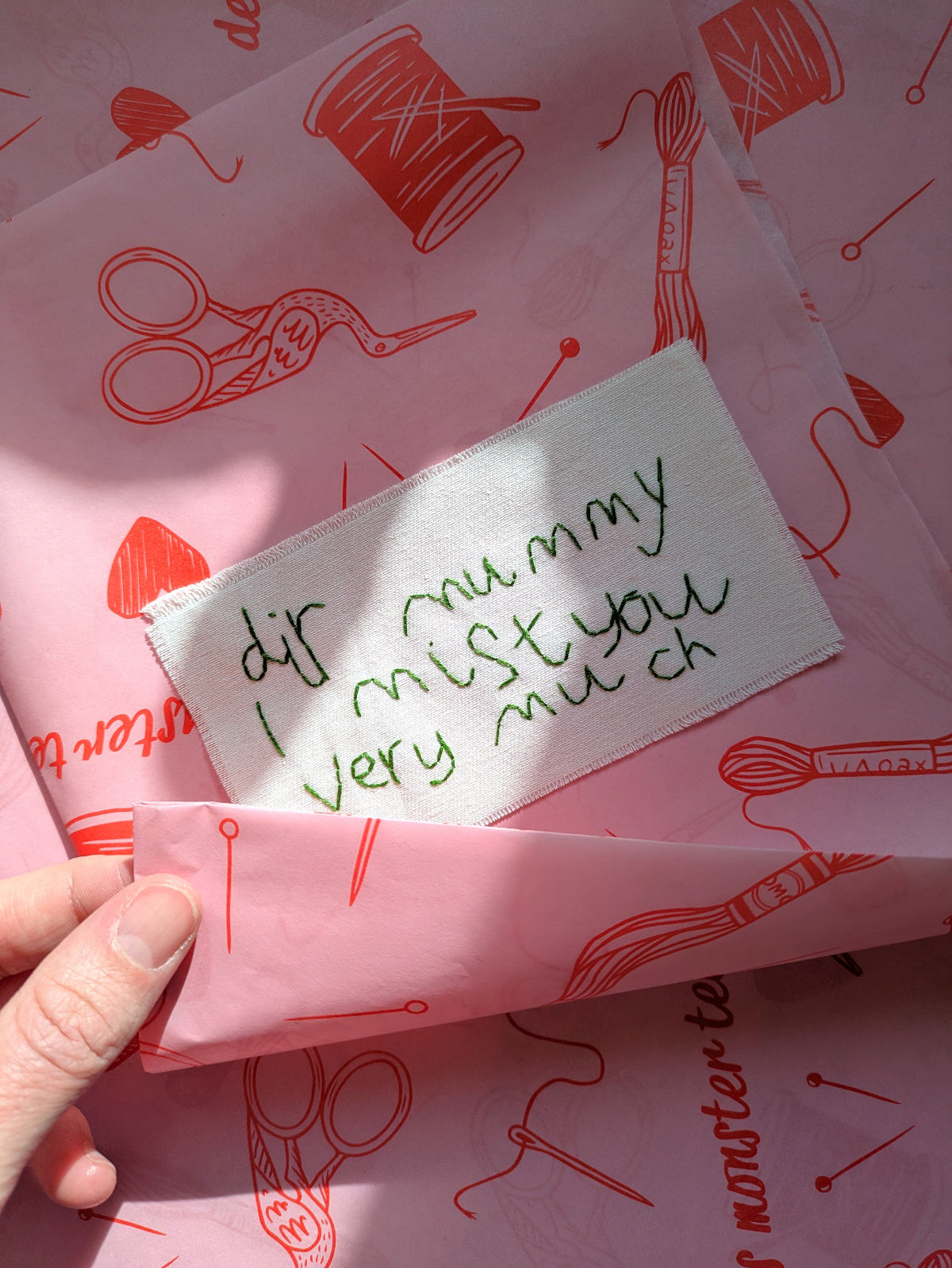 personalised child's handwriting hand embroidered on cotton being wrapped in tissue paper