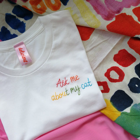 organic cotton white slogan tshirt, embroidered with ask me about my cat in rainbow threads. funny birthday gift for cat mum or cat lover