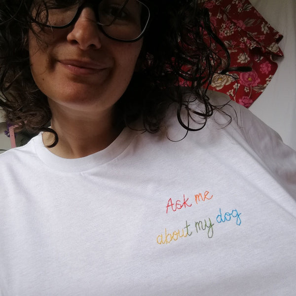 organic cotton white slogan tshirt, embroidered with ask me about my dog in rainbow threads. funny birthday gift for dog mum or dog lover