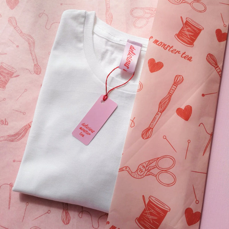 White t-shirt with pink pattern and tag on a matching pink background
