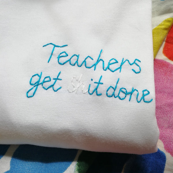 organic cotton white slogan t-shirt, embroidered with 'teachers get shit done' in blue thread. funny thank you gift for teacher