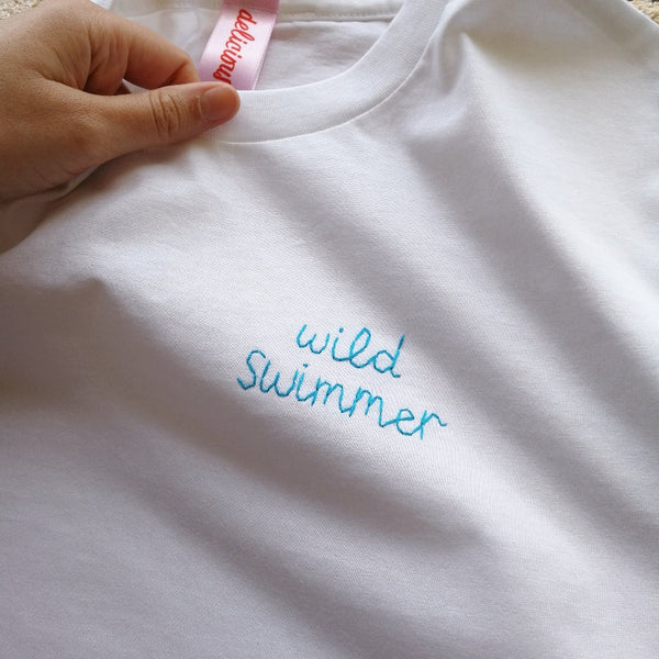 unisex personalised t-shirt, made from white organic cotton, and hand embroidered with custom slogan in blue thread, as christmas gift or birthday gift for wild swimmer